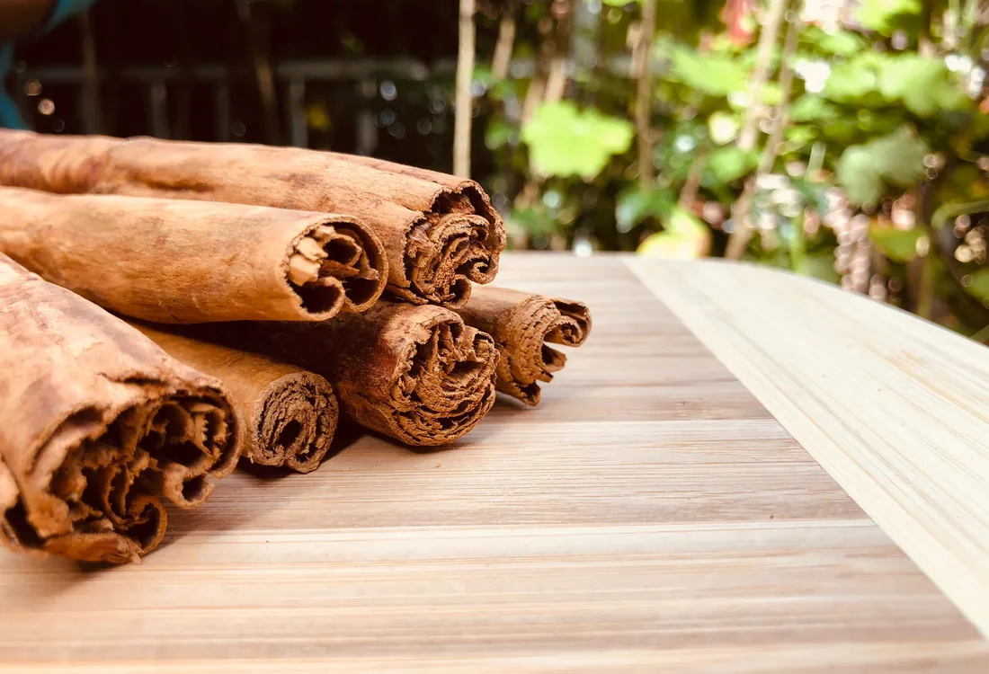 Hand-rolled Ceylon cinnamon quills on a wooden board, the thin bark rolled into tight layers