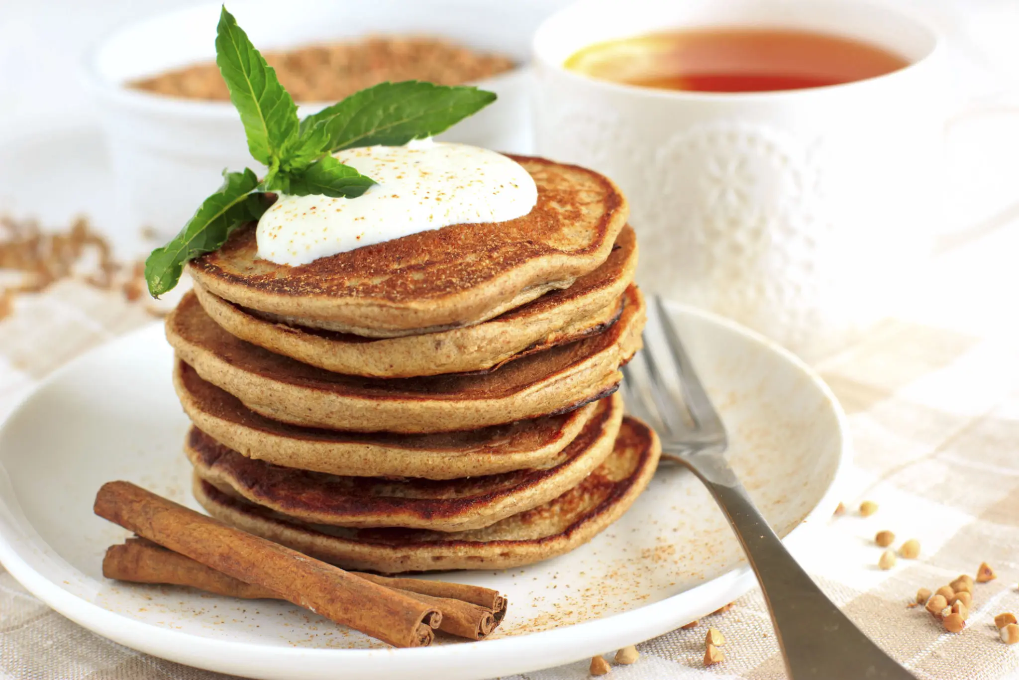 A stack of cinnamon pancakes topped with yoghurt and mint