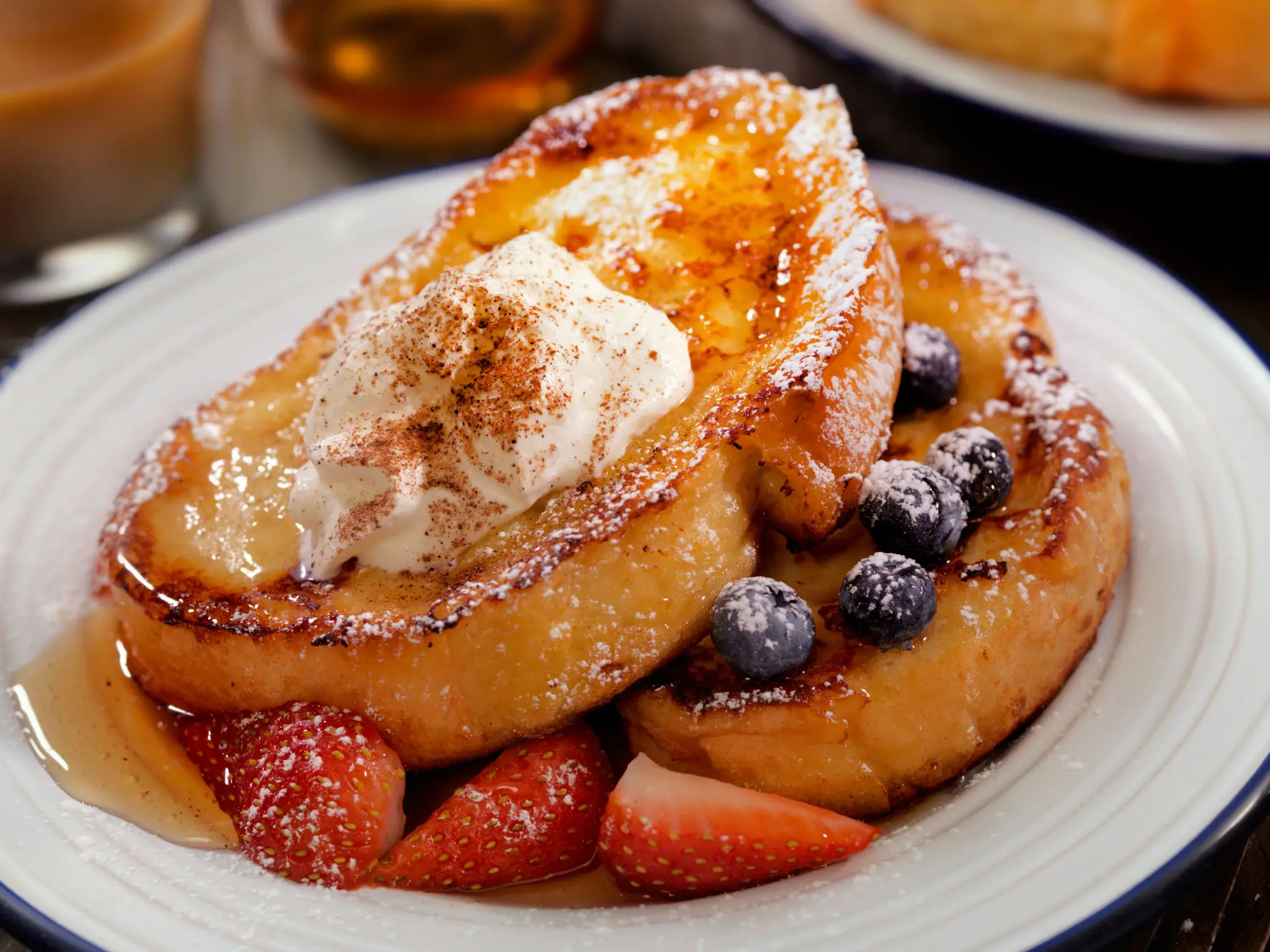 French toast with cream, strawberries and blueberries, dusted with cinnamon