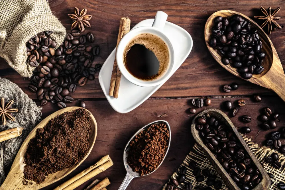 A cup of black coffee with a cinnamon stick resting on the saucer