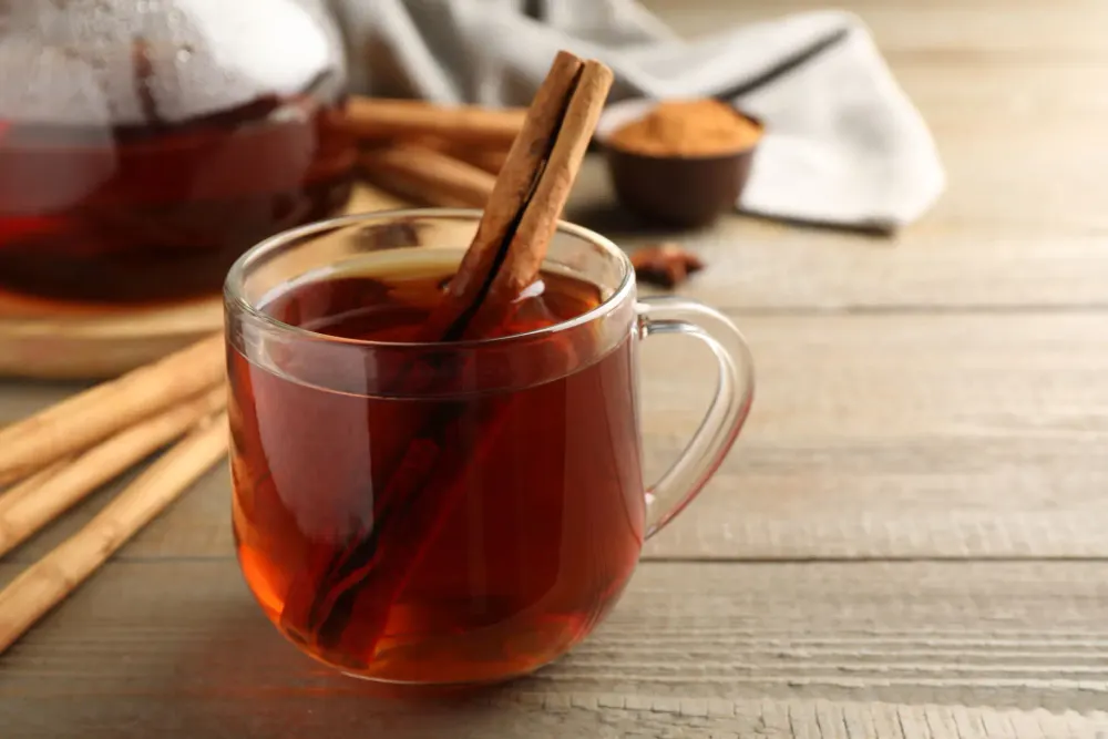 A glass mug of cinnamon tea with a cinnamon stick