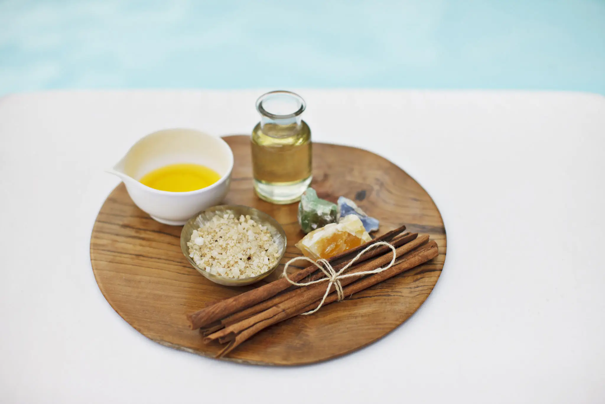 Essential oils, bath salts and cinnamon sticks on a wooden platter