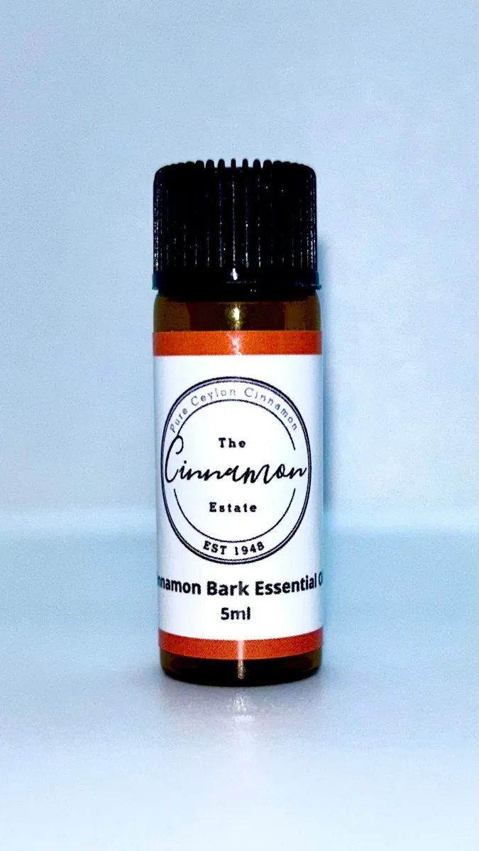 An amber dropper bottle of The Cinnamon Estate pure Ceylon cinnamon bark essential oil, with a rust orange striped label.
