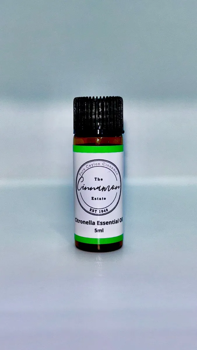 An amber dropper bottle of The Cinnamon Estate citronella essential oil, with a bright green striped label.