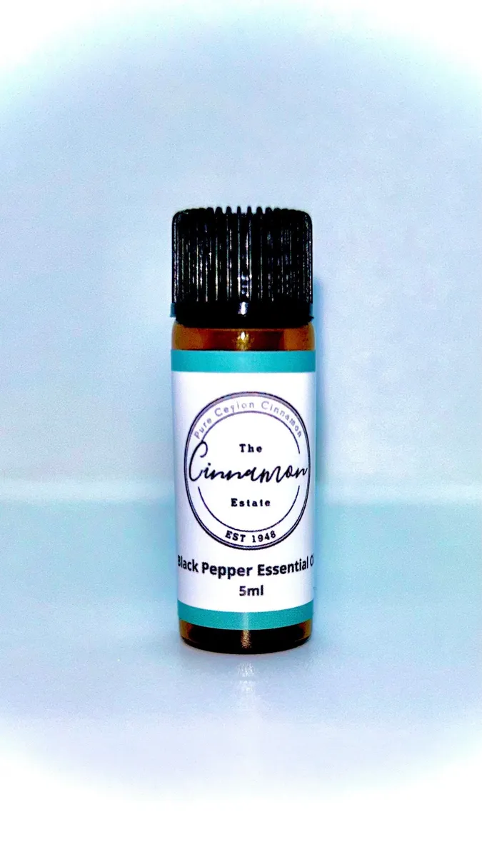 An amber dropper bottle of The Cinnamon Estate black pepper essential oil, with a teal striped label.